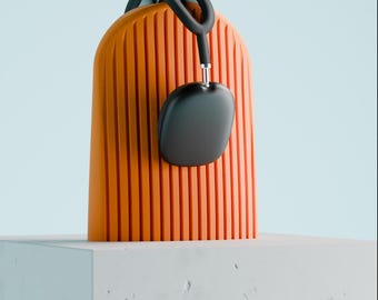 May include: A pair of black over-ear headphones with a rounded rectangular shape and a thin headband, resting on top of a bright orange, vertically ribbed, arch-shaped stand that features a smooth, consistent texture throughout.