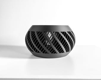 May include: A matte black spherical bowl featuring a complex, open-work lattice pattern of diagonal slats. The object has a solid, smooth rim at the top and a matching solid base, creating a hollow, cage-like structure with a dark, uniform finish.