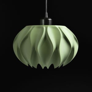 May include: A pale green pendant light fixture featuring a rounded, bulbous shade with vertical, wave-like pleats that create a scalloped bottom edge. The shade is attached to a black cylindrical mount and a black cord for suspension.