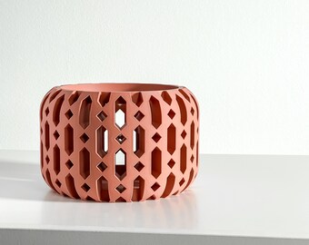 May include: A cylindrical terracotta-colored planter featuring a repeating geometric cutout pattern of vertical elongated hexagons and small diamonds. The vessel has a wide open top and a solid base, showcasing a matte finish throughout its structure.
