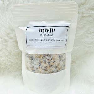 May include: White pouch with a label that reads "Empath Ritual Salt" and "Reiki Infused - Quartz Crystal - Many Uses". The pouch contains a white salt with lavender and other herbs.