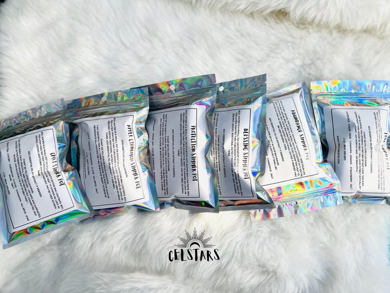 May include: Five iridescent holographic pouches with text that reads "Abundance Simmer Pot", "Blessing Simmer Pot", "Protection Simmer Pot", "Apple Cinnamon Simmer Pot", and "Chai Vanilla Simmer Pot".