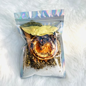 May include: A clear, iridescent zip-top bag filled with dried herbs, spices, and salt. The contents include dried orange slices, bay leaves, and other aromatic ingredients. The bag is sealed and ready for use.