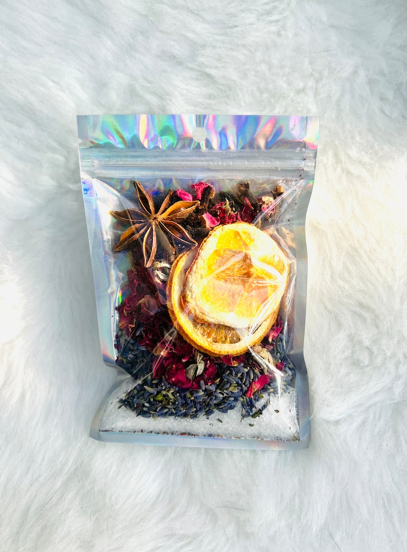 May include: A clear plastic bag filled with a bath soak mixture. The mixture includes dried orange slices, star anise, lavender buds, and rose petals.