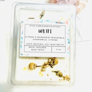 May include: A white soy wax melt in a clear plastic container with dried chamomile flowers and gold glitter. The label reads "UPLIFT Citron & Mandarin Fragrance. Chamomile, Citrine 100% Natural Soy Wax Melts Reiki Infused Non-Toxic 2 oz ETSY.COM/SHOP/CELSTARS".