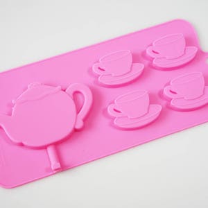 May include: Pink silicone mold for making chocolate teacups and a teapot. The mold has four teacup and saucer molds and one teapot mold.