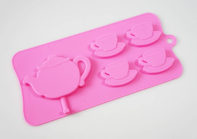 May include: Pink silicone mold for making chocolate teacups and a teapot. The mold has four teacup and saucer molds and one teapot mold.