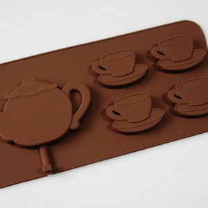 May include: Brown silicone mold for making chocolate teacups and a teapot. The mold has four teacup and saucer molds and one teapot mold.