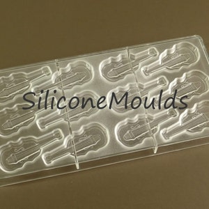 May include: Clear plastic mold with 9 cavities shaped like violins. The mold is designed for making chocolate or other edible treats.