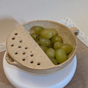 May include: A set of three ceramic mugs with a speckled, matte finish. The mugs are in shades of cream, light gray, and dark gray. Each mug has a simple, minimalist design, perfect for coffee or tea.