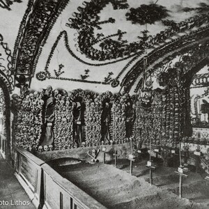 May include: A black and white photograph of an ossuary interior featuring walls and ceilings intricately decorated with human skulls and bones arranged in patterns. Several robed figures stand within alcoves, and small crosses are placed.