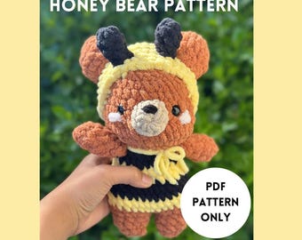 Peut inclure: Une peluche d'ours en crochet, habillée en abeille avec des rayures jaunes et noires. L'ours a une fourrure brune, des antennes noires et un bonnet jaune. Le texte indique "HONEY BEAR PATTERN" et "PDF PATTERN ONLY".