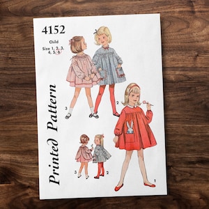 May include: A vintage printed pattern for a child's dress, featuring illustrations of girls in various dress styles. The pattern includes sizes 1, 2, 3, 4, 5, and 6. The image is on a white background with the text "Printed Pattern".