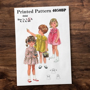 May include: A vintage sewing pattern for a child's dress. The pattern is for sizes 1/2, 1, 2, 3, 4, 5, 6, and 6X. The pattern shows three girls wearing different versions of the dress. The pattern is called "Printed Pattern 4050BP".