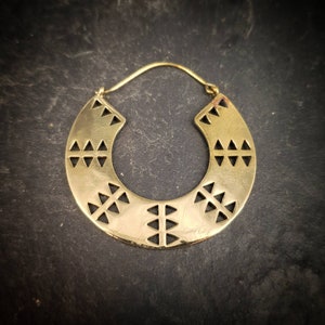 Könnte beinhalten: Goldene Creolen mit einem geometrischen Muster ausgeschnitten. Die Ohrringe sind aus Messing und haben ein schlichtes, modernes Design.