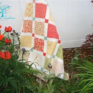 May include: A patchwork quilt featuring a grid of square fabric blocks in shades of coral, yellow, and light green, separated by white sashing and small red cornerstones. The quilt displays a repeating floral pattern across its various fabric sections.
