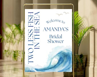May include: A gold metal sign with a white sign that reads "TWO LESS FISH IN THE SEA" and "Welcome to AMANDA'S Bridal Shower." The sign features a blue watercolor wave design and two small bird illustrations.