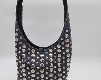 May include: Black leather shoulder bag with a curved handle. The bag is covered in silver metal studs of varying sizes. The handle is black and the stitching is white.