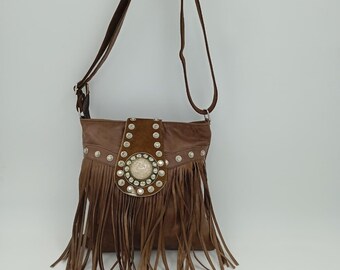 Può includere: Borsa a tracolla in pelle marrone con frange e borchie color argento. La borsa presenta una patta decorativa con un grande ornamento rotondo e una lunga tracolla regolabile. Il design della borsa è di ispirazione western.