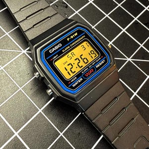 Reloj Casio F-91W con modificación de temperatura en color naranja y retroiluminación uniforme (dispersor óptico de luz), modificado a mano por FlexureLabs.