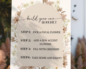 May include: A white sign on a wooden easel with the text "build your own BOUQUET". The sign has a floral design and instructions: Pick a focal flower, add accent flowers, fill with greenery, and take home and enjoy.