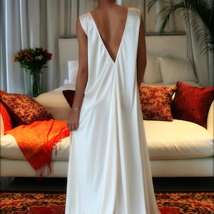 May include: A white satin slip dress with a deep V-neckline and lace trim. The dress is worn by a person with red hair and is photographed against a white background.