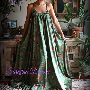 Puede incluir: Un vestido largo verde con estampado floral y de p&aacute;jaros. El vestido tiene tirantes finos y un escote fruncido. El texto "Sarafina Dreams" es visible. El vestido se usa en una habitaci&oacute;n con muebles y decoraci&oacute;n antiguos.