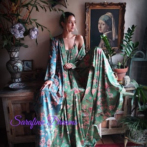 Puede incluir: Un vestido largo con estampado floral y una bata a juego en tonos verde y turquesa. El vestido presenta un delicado estampado floral rosa y detalles de mariposas. La imagen incluye el texto "Sarafina Dreams" en cursiva.