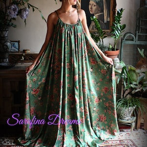 Puede incluir: Un vestido largo verde con estampado floral y de p&aacute;jaros. El vestido tiene tirantes finos y un escote fruncido. La tela es suave y fluida. El escenario es una habitaci&oacute;n de estilo vintage.