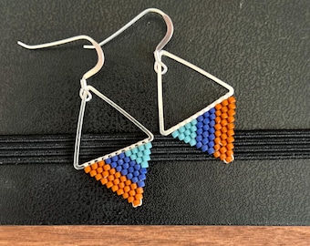 May include: A pair of silver triangle earrings with orange, blue, and turquoise beaded accents.