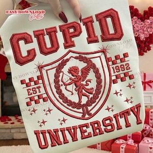 Puede incluir: Sudadera crema con texto y diseño bordados en rojo. El diseño presenta las palabras "CUPID UNIVERSITY" y "EST 1992". Un escudo gráfico representa a Cupido con arco y flecha, rodeado de laureles y estrellas.