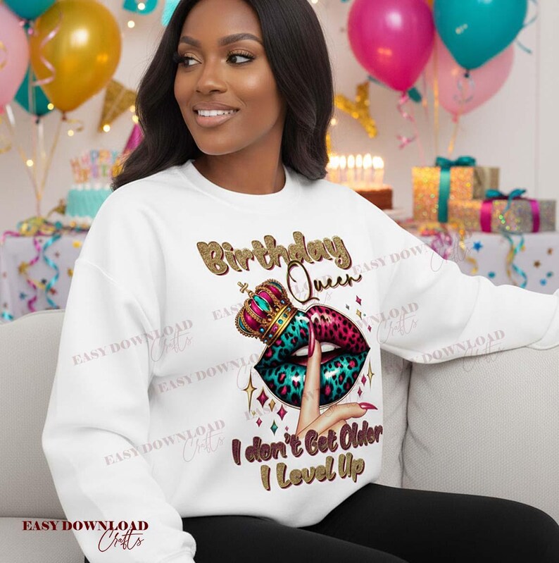 May include: White sweatshirt with a graphic design featuring the text "Birthday Queen" in gold glitter lettering. The design includes a crown, lips with a leopard print, and the phrase "I don't Get Older I Level Up."