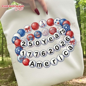 Puede incluir: Sudadera blanca con un diseño patriótico con cuentas rojas, blancas y azules. El diseño incluye el texto "250 años 1776 2026 America" y elementos decorativos como estrellas, lazos y cupcakes. Ideal para celebrar el aniversario nacional.