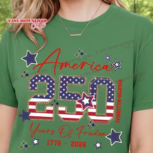 May include: Green t-shirt with a patriotic design celebrating America's 250th anniversary. The design features the word "America" in red script, the number "250" in a star-spangled pattern, and the text "Years Of Freedom 1776-2026."