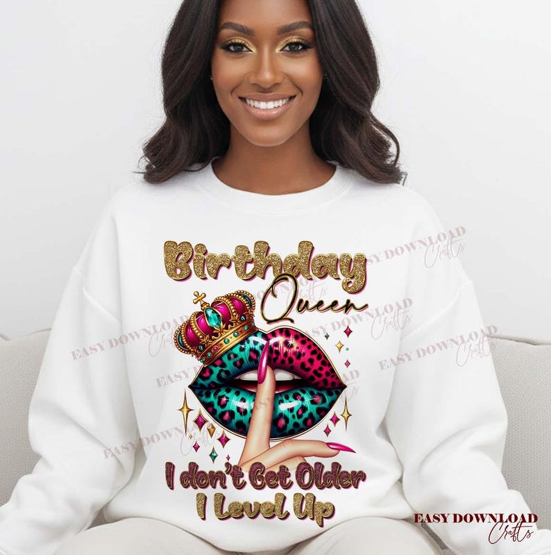 May include: White sweatshirt with a graphic design featuring the text "Birthday Queen". The design includes a crown, lips with a leopard print, and the phrase "I don't Get Older I Level Up".