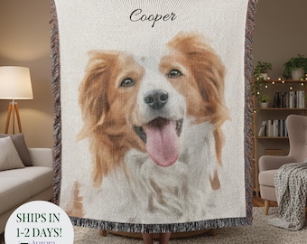 May include: A woven throw blanket featuring a portrait of a dog with brown and white fur, and a pink tongue. The dog's name, "Cooper", is written above the image. The blanket has a fringed edge.