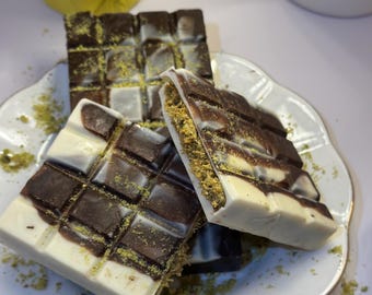 May include: Three chocolate bars with white chocolate and a green sprinkle on a white plate with a gold rim.