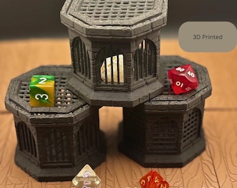 May include: A 3D-printed Gothic dice jail in dark gray, with a cage-like design. The image shows three jails, each with a dice inside. The text "Gothic dice jail" is at the bottom, and "3D Printed" is in the upper right.