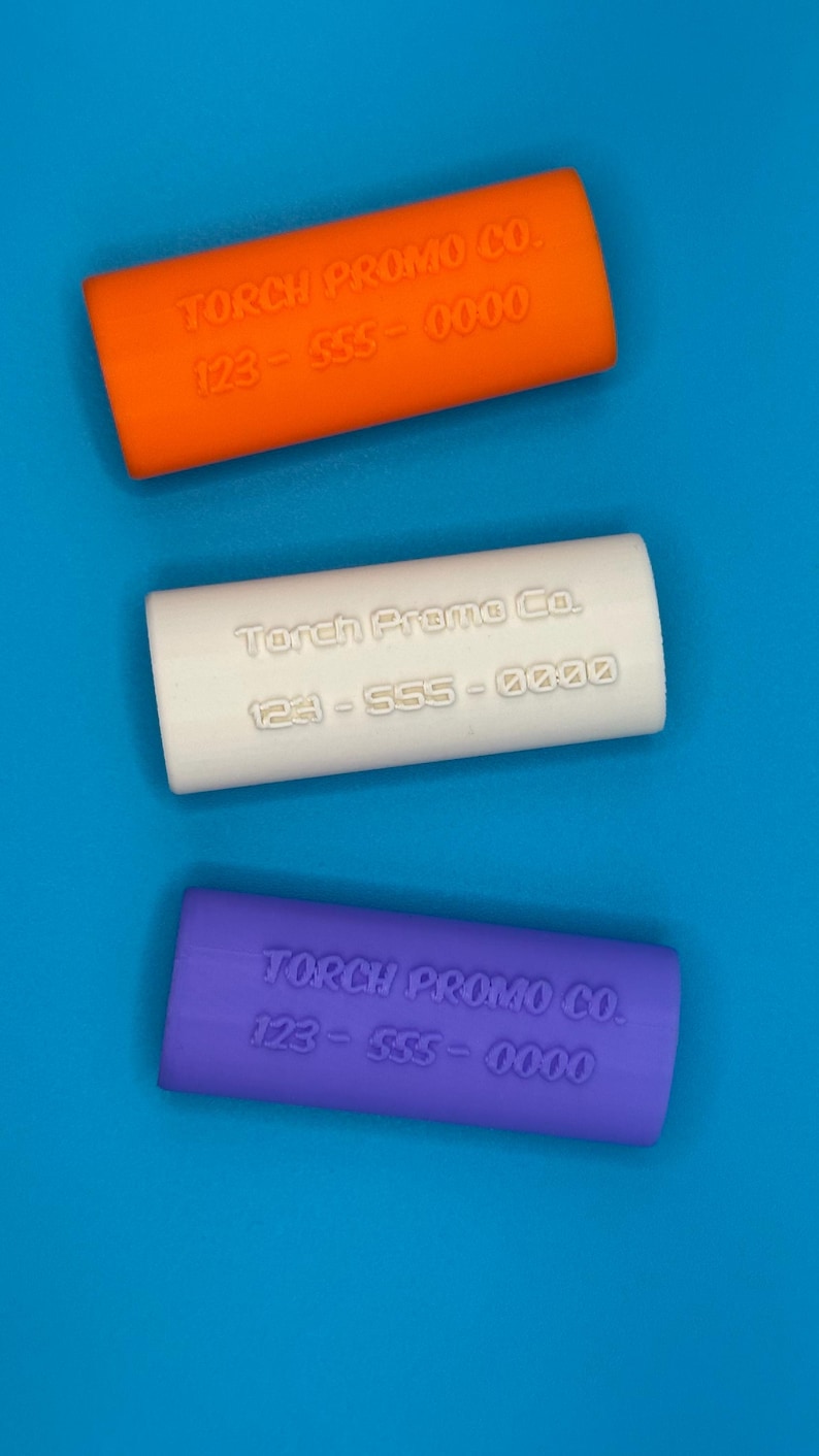 May include: Three silicone phone grips in orange, white, and purple. Each grip has the text "Torch Promo Co. 123-555-0000" embossed on it.