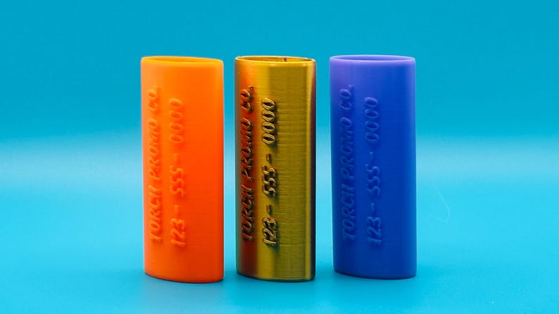 May include: Three cylindrical containers with different colored caps. The orange container has the text "Torch Premium Co. 123-555-0000" printed on it. The gold container has the text "Torch Premium Co. 123-555-0000" printed on it. The blue container has the text "Torch Premium Co. 123-555-0000" printed on it.