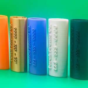 May include: Five different colored cylindrical tubes with the text "Torch Brand Co. 123-555-0000" embossed on each tube. The tubes are orange, gold, blue, white, and black.