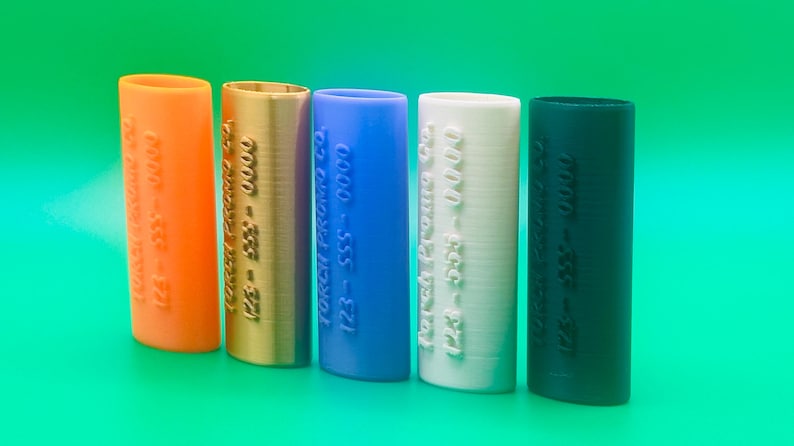 May include: Five different colored cylindrical tubes with the text "Torch Brand Co. 123-555-0000" embossed on each tube. The tubes are orange, gold, blue, white, and black.
