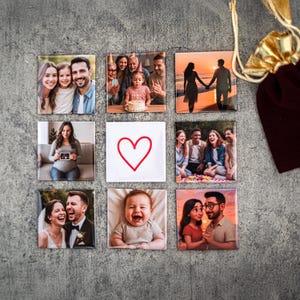 May include: Nine square photo magnets featuring various images of families and couples. The magnets are arranged in a grid pattern on a grey background. A red heart is in the centre of the grid.