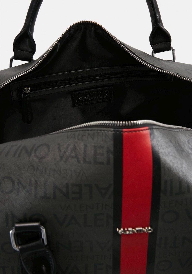May include: Black duffel bag with the Valentino logo and text pattern. The bag features a red stripe down the center, black handles, and a zippered main compartment. The interior is black.