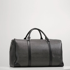 May include: A dark gray duffel bag with black handles and trim. The bag features the repeating text "VALENTINO" in a lighter gray pattern across its surface. The bag has a rectangular shape with a zipper closure and two top handles.