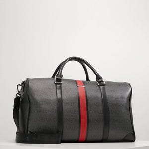 May include: A dark gray duffel bag with black handles and a shoulder strap. The bag features a red stripe down the center and the word "VALENTINO" printed repeatedly in a lighter gray.