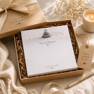 May include: A gift box with a notepad that reads "Sacred Balance" and "Find harmony within." The box also contains a candle, a pen, and a tag that says "Take a moment for you."