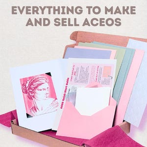 May include: A cardboard box containing art supplies for creating and selling ACEO cards. The kit includes pastel-colored cardstock, a pink envelope, and a guide titled "ACEO Quick Start Guide" featuring a pink illustration of a classical bust.