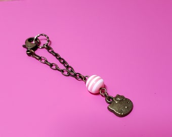 May include: A bronze chain charm with a pink and white striped bead and a Hello Kitty charm.