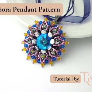 Pu&ograve; includere: Primo piano di un ciondolo con una gemma blu centrale circondata da un motivo floreale. Il ciondolo presenta perline rosa, blu, gialle e argentate. Il testo "Cipora Pendant Pattern" &egrave; in alto e "Tutorial | by Tiszi" in basso.